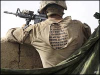 The tattoo of a US Marine is seen through a hole in his shirt, as he stands guard at a compound in Afghanistan July 8